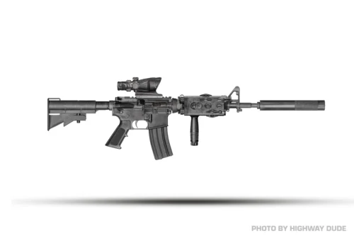 Black semi-automatic rifle with scope and suppressor mounted, shown in profile on a white background