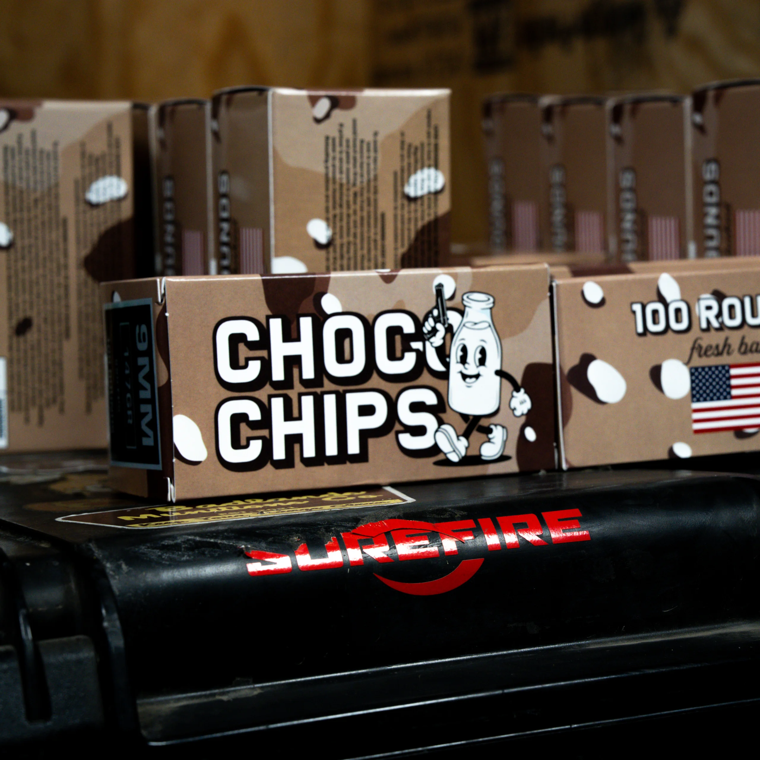 choco chip 2 – Badlands Munitions Co Close-up of brown cookie boxes on a supermarket shelf with a cartoon bottle and white polka dots, labeled chocolate chips cookie mix (grouped packaging).