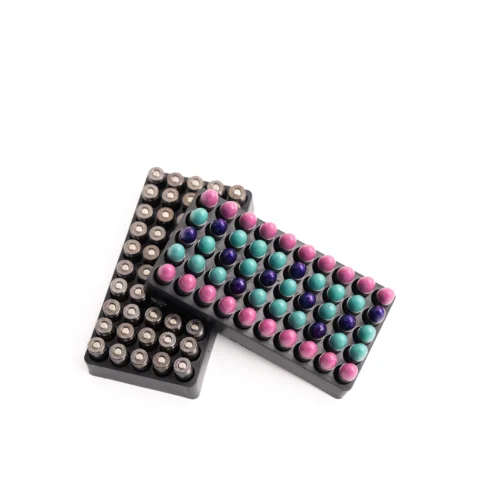 Assorted marker pens with colorful round caps arranged in black trays on a white surface.